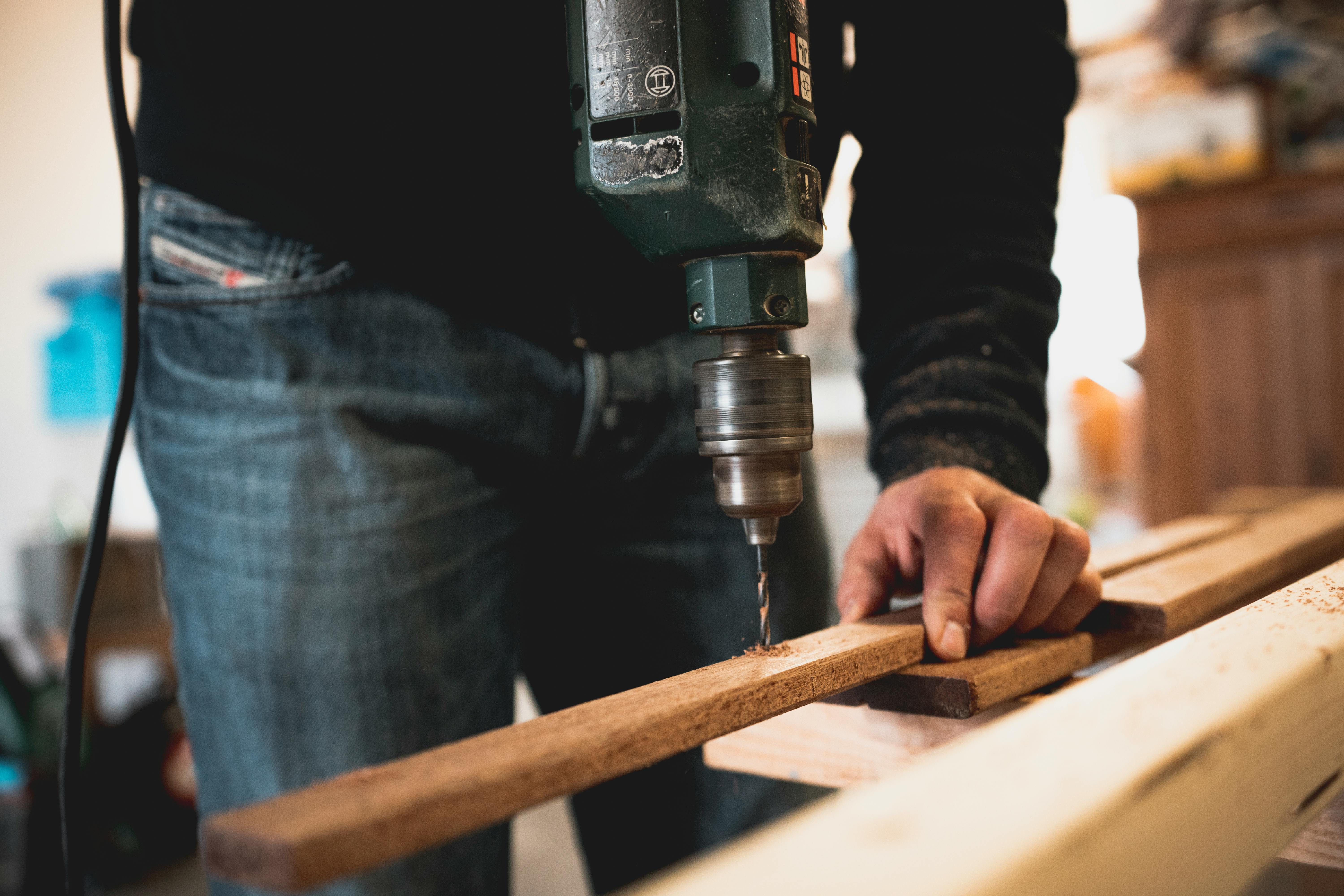 Woodworker drilling wood with protective gear
